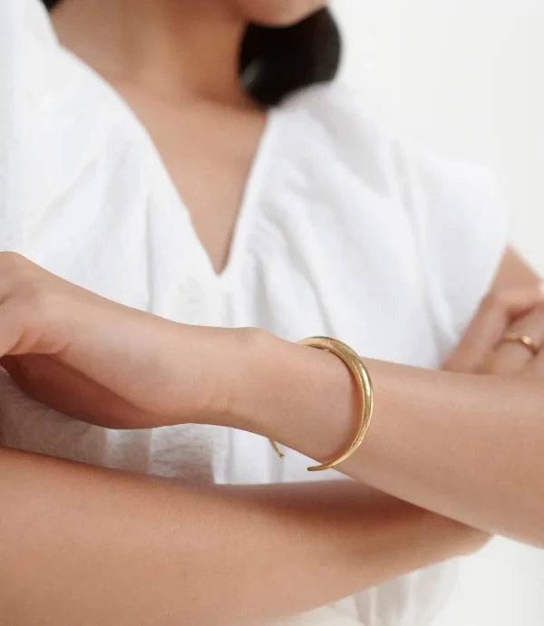 Close-up of crossed arms wearing gold bracelet