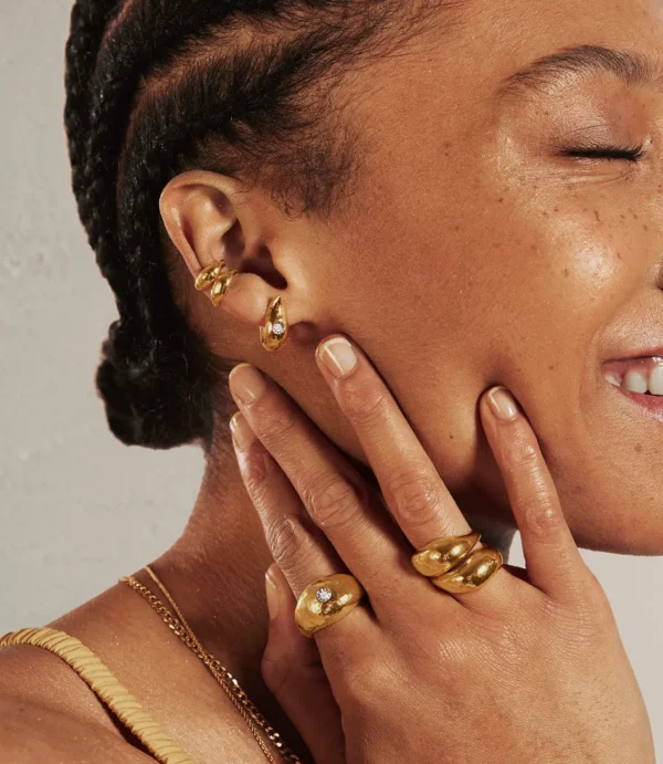Close-up of ear with gold earrings and rings