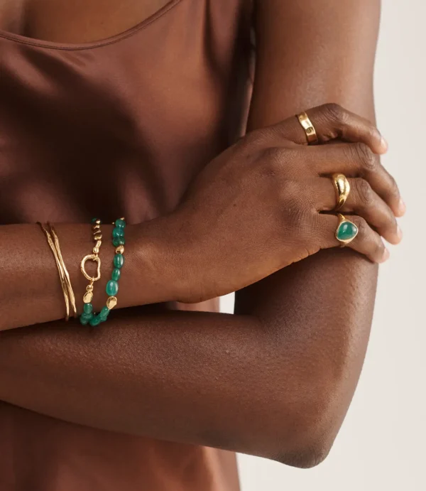 Close-up of hands wearing gold and green jewelry