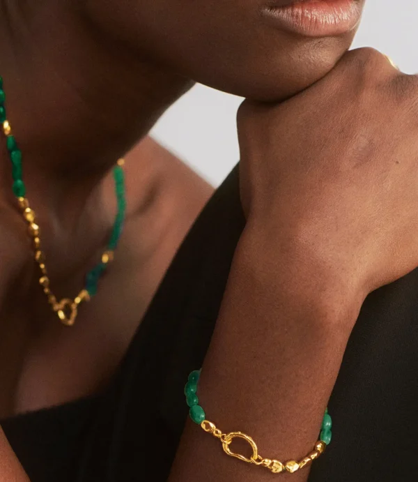 Close-up of chin and hand wearing green jewelry