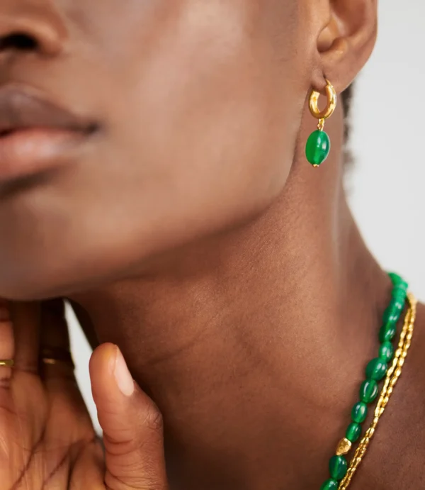 Ear wearing gold hoop with green bead