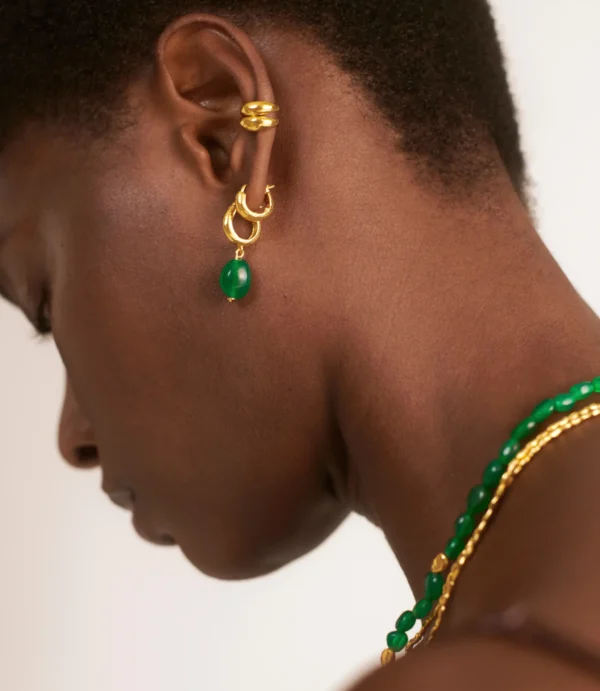 Close-up ear with gold earrings and green bead