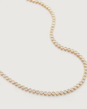 Gold bezel-set diamond necklace on white background