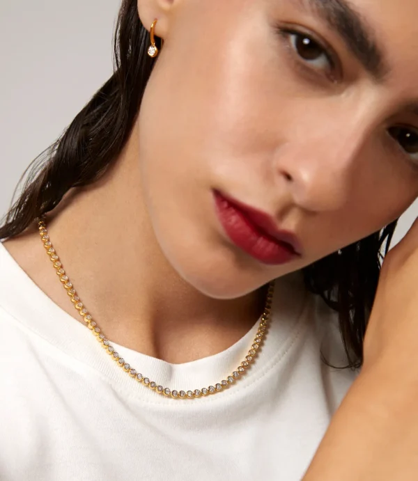 Close-up of woman wearing gold necklace and earring