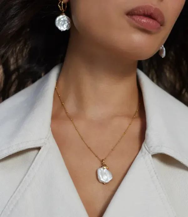 Close-up of neck wearing pearl necklace and earrings