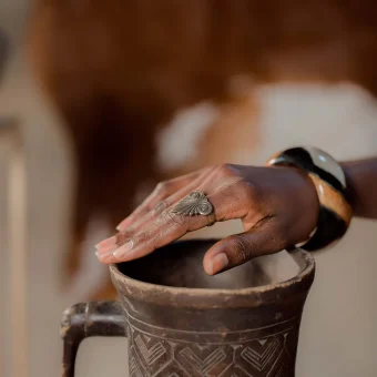 Hand with ring on ornate clay jug